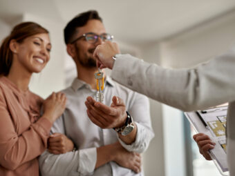 closeup real estate agent giving couple keys their new home scaled