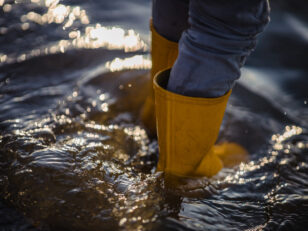 person blue denim jeans yellow boots standing water 1 scaled